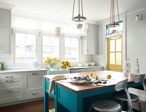 Bright, sun-drenched kitchen with painted yellow door and teal island Bright, sun-drenched kitchen with painted yellow door and teal island