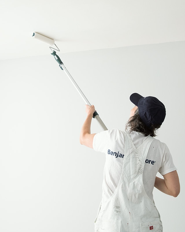 A pro painter rolls paint on a customer’s ceiling A pro painter rolls paint on a customer’s ceiling