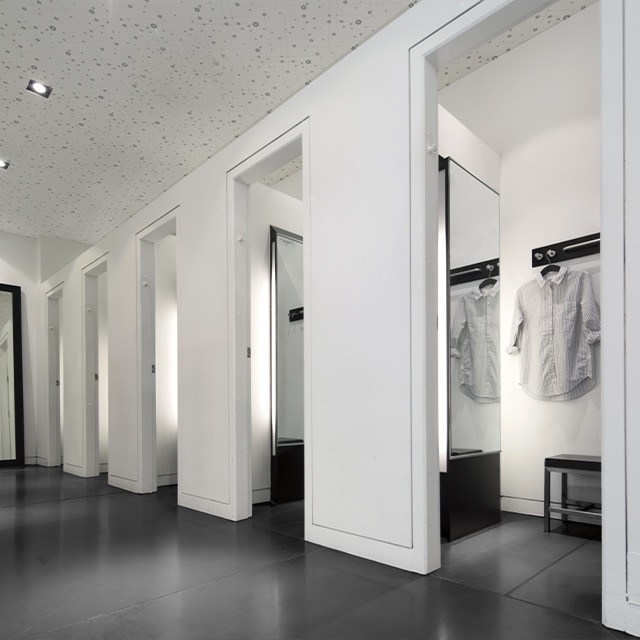 A scuff-free, white-painted dressing room area with open doors, mirrors, and a black floor. A scuff-free, white-painted dressing room area with open doors, mirrors, and a black floor.